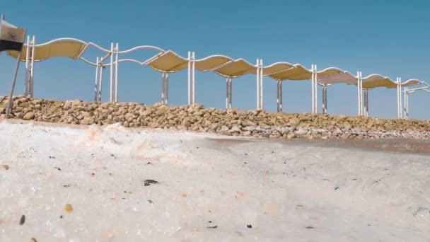 イスラエルの死海のほとりにある天然の白い塩の結晶のシネマグラフ 穏やかな熱帯波がビーチで転がっています スローモ スローモーション 高速カメラ — ストック動画