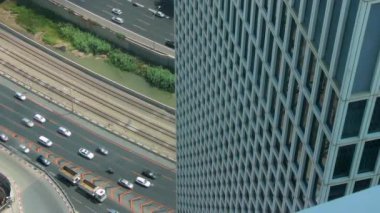 Tel Aviv 'deki Azrieli kulesi manzaralı Ayalon otobanındaki trafik sineması. İki araba bir döngü içinde yolda ilerliyor. Üç binadan birinin içinden yüksek bir açı..