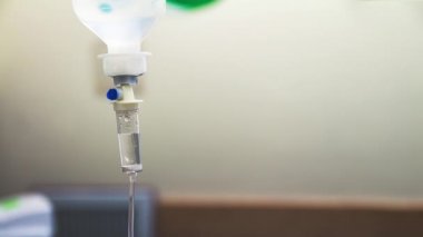 Hastane odasında damardan akan sıvı salin damlalarının sinemagrafı. Beyaz arka planda damardan serum damlası tuzuna yaklaş. Döngü, seçici odak ve boşluğu kopyala.