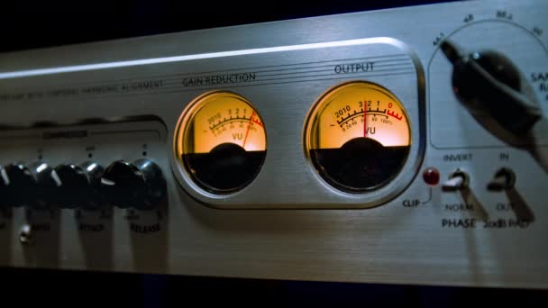 La cinématographie d'un VU-mètre analogique se déplace en synchronisation avec le niveau sonore. Gros plan sur la console d'égalisation du mixeur sonore avec de nombreux boutons dans un studio d'enregistrement. Boucle avec mise au point sélective .
