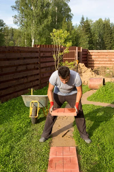 Man puts concrete tiles on the path — Stock Image Man puts concrete tiles on the path Stock Image