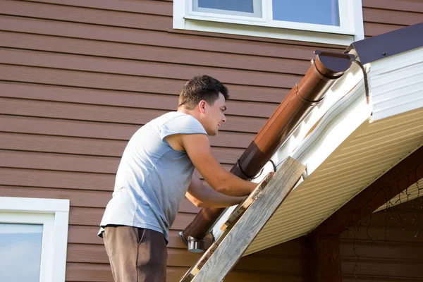 Man fäster gutter på taket på verandan — Stockfoto