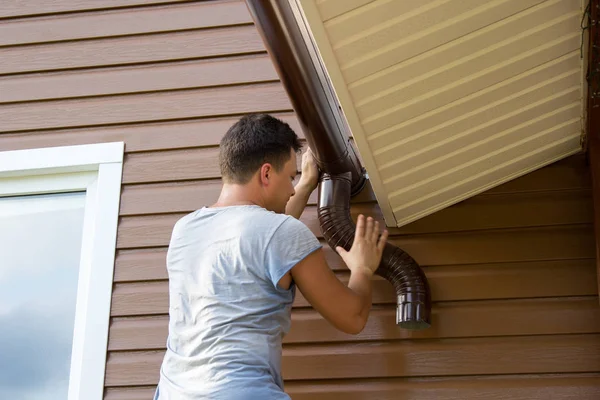 Man fäster gutter på taket på verandan — Stockfoto