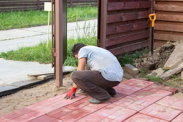 Человек кладет красные бетонные плиты — стоковое фото