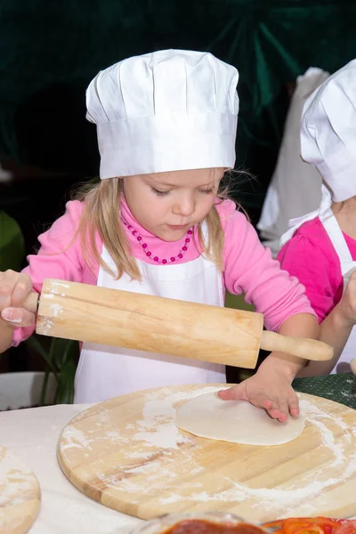 Девочка в шляпе шеф-повара готовит пиццу — стоковое фото