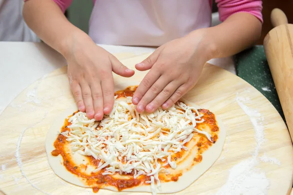 Девочка в шляпе шеф-повара готовит пиццу — стоковое фото