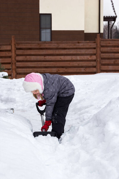 Girl takes snow off the track with a shovel