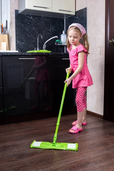 Little girl washes floor with a mop