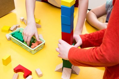 Çocuklar masanın üstünde ahşap blokların kule inşa