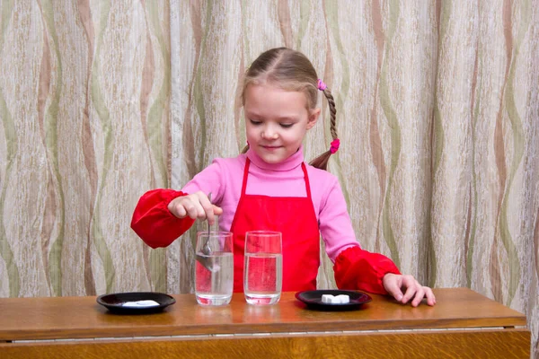 Хорошенькая маленькая девочка проводит эксперименты с физической водой дома — стоковое фото