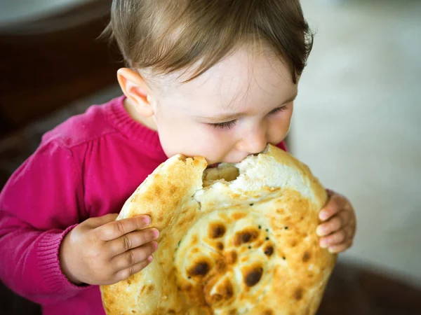 Holding ve büyük parça ekmek ısırma bir yaşında bebek