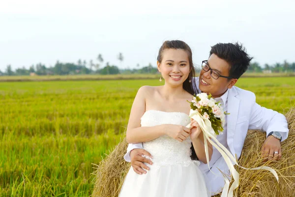 亚洲新郎新娘躺在稻田稻草地上 — 图库照片