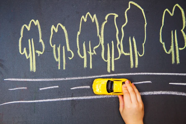 child playing with the car close. one small car goes on the road