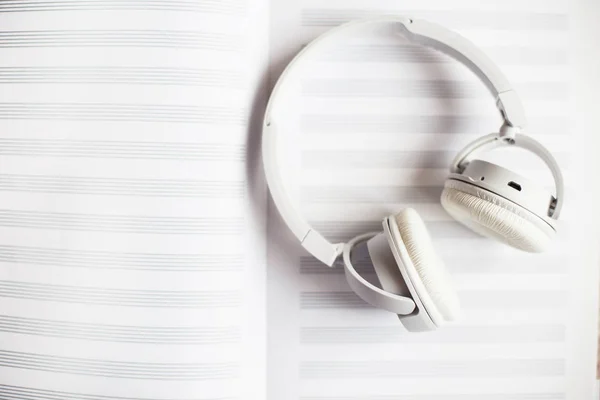 white headphones on a notebook for notes on a white background