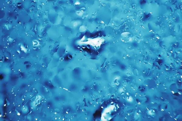 water drops on a blue background. Abstract blue background. Water drops on glass. Natural background toned in blue.