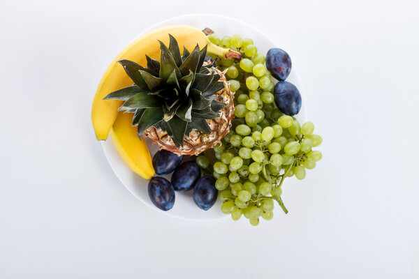 Useful fruit on a plate on a white background in the studio. Ban