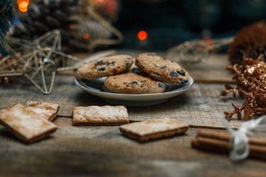 Güzel genel kavram. Çikolata kurabiye ahşap arka plan üzerinde beyaz bir tabakta. Yakın bir Noel ağacı, oyuncak, çay, çelenk ve Noel oyuncaklar standları.