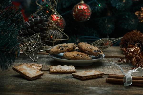 Güzel genel kavram. Çikolata kurabiye ahşap arka plan üzerinde beyaz bir tabakta. Yakın bir Noel ağacı, oyuncak, çelenk ve Noel oyuncaklar standları.