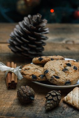 Çikolatalı kurabiye rustik arka plan üzerinde. Yakındaki yalan tarçın sopa ve konileri. Oyuncaklar ve çelenk ile ağacı gerisindedir. Yeni yıl tatili.