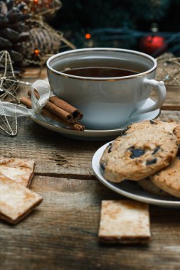 Güzel genel kavram. Çikolata kurabiye ve çay bir ahşap arka plan beyaz tabakta. Yakın bir Noel ağacı, oyuncak, çelenk ve Noel oyuncaklar standları.