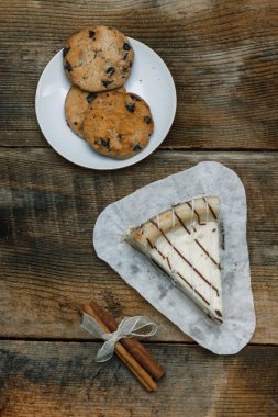 Güzel ev yapımı pasta peynirli kek tarçın çubuğu ile ahşap arka plan üzerinde beyaz kağıt üzerinde. Noel hediyeler, Noel ağacı ve oyuncaklar. Yılbaşı kutlamak için tasarlandı. Yukarıdan görüntülemek.