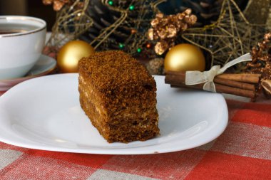 Damalı bir masa örtüsü ile çay, bisküvi, tarçın bir yılbaşı Noel ağacı bir arka plan üzerinde beyaz bir tabağa kek. Yeni konsept. Tatil için.