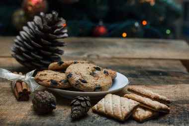 Çikolatalı kurabiye rustik arka plan üzerinde. Yakındaki yalan tarçın sopa ve konileri.
