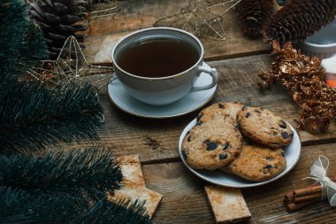 Güzel genel kavram. Çikolata kurabiye ahşap arka plan üzerinde beyaz bir tabakta. Yakın bir Noel ağacı, oyuncak, çay, çelenk ve Noel oyuncaklar standları.