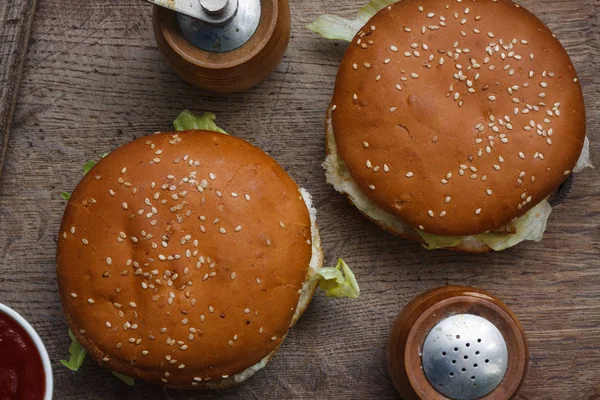 Concept de table de fête alimentaire. Sandwichs aux saucisses grillées avec deux hamburgers, pommes de terre frites et diverses sauces servies sur une table rustique d'en haut . — Photo