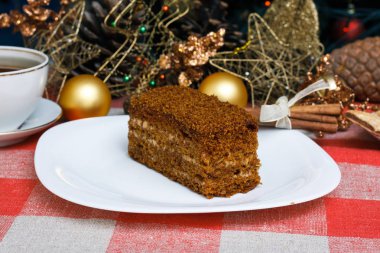 Damalı bir masa örtüsü ile çay, bisküvi, tarçın bir yeni yıl Noel ağacı bir arka plan üzerinde beyaz bir tabağa kek. Yeni konsept. Tatil için.