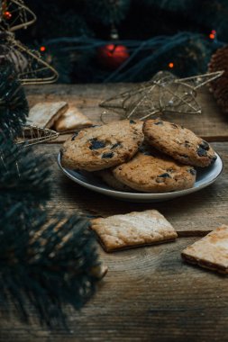 Güzel genel kavram. Çikolata kurabiye ahşap arka plan üzerinde beyaz bir tabakta. Yakın bir Noel ağacı, oyuncak, çelenk ve Noel oyuncaklar standları.