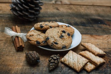 Çikolatalı kurabiye rustik arka plan üzerinde. Yakındaki yalan tarçın sopa ve konileri.