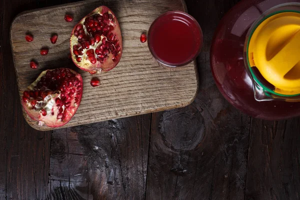 Pomegranate juice with sliced pomegranate on a wooden board. — Stock Photo, Image