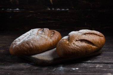 İki ekmek un ahşap arka plan üzerinde siyah. Ekmek reklam. Yaslanmış un.