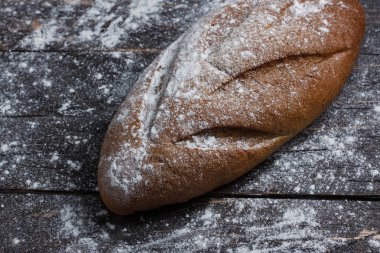 Bir siyah ekmek un ahşap arka plan ile. Ekmek reklam. Yaslanmış un. Yukarıdan görüntülemek.