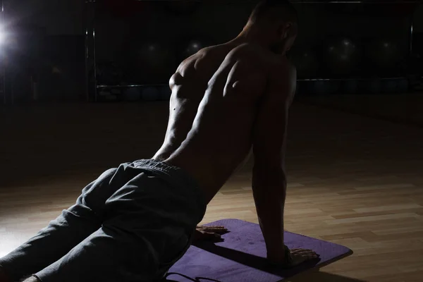 Handsome muscular man flexing back muscles on bench in gym. Blac — Stock Photo, Image