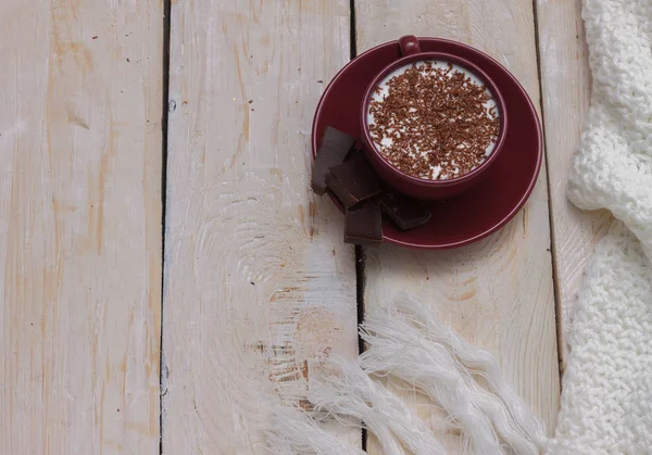 Chocolate de leite em uma xícara em um pires em um fundo de madeira . — Fotografia de Stock