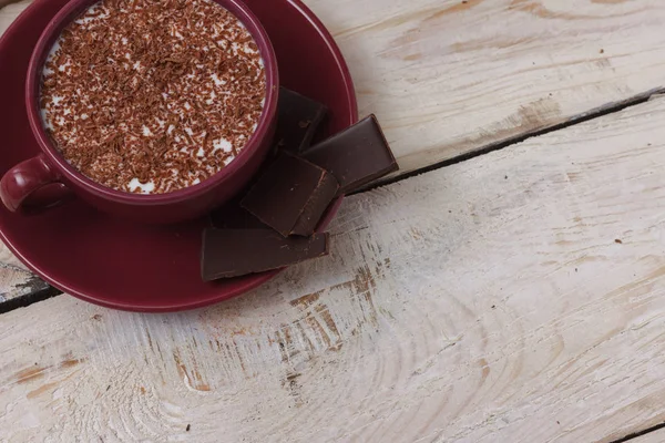 Chocolate de leite em uma xícara em um pires em um fundo de madeira. Clos — Fotografia de Stock