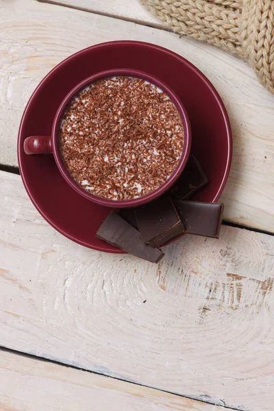 Chocolate de leite em uma xícara em um pires em um fundo de madeira leve — Fotografia de Stock