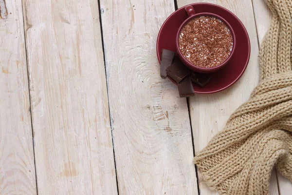 Milk chocolate in a cup on a saucer on a light wooden background — Stock Photo, Image