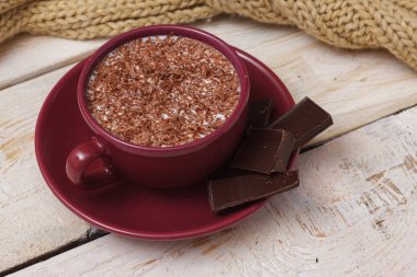 Sütlü çikolata bir fincan hafif ahşap arka plan üzerinde bir daire üzerinde