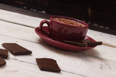 Sütlü çikolata bir fincan hafif ahşap arka plan üzerinde bir daire üzerinde