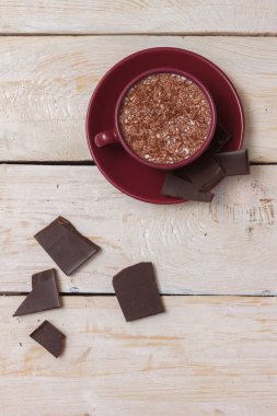 Sütlü çikolata bir fincan hafif ahşap arka plan üzerinde bir daire üzerinde