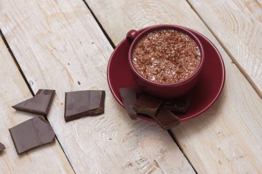 Sütlü çikolata bir fincan hafif ahşap arka plan üzerinde bir daire üzerinde