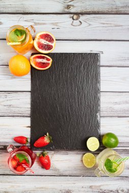 Summer drinks. Fresh freshes on a slate board. View from above. Orange, lemon and strawberry fresh.
