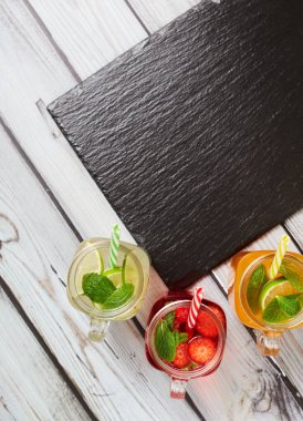 Summer drinks. Fresh freshes on a slate board. View from above. Orange, lemon and strawberry fresh.
