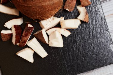 Whole coconut with pieces on a dark background.