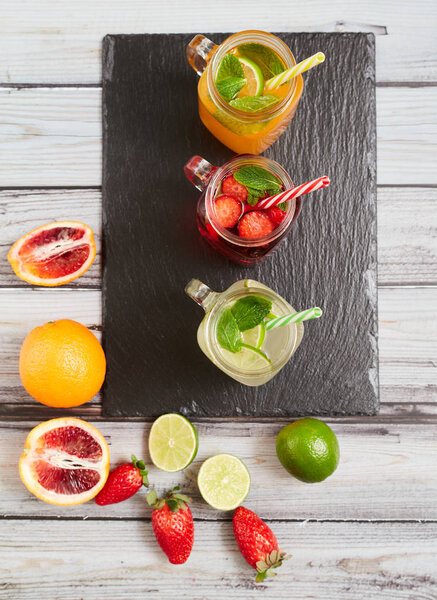 Summer drinks. Fresh freshes on a slate board. View from above. Orange, lemon and strawberry fresh.