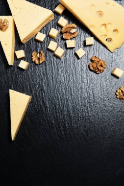 Koyu arkaplanda ceviz olan peynir parçaları..