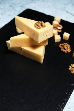 Koyu arkaplanda ceviz olan peynir parçaları..